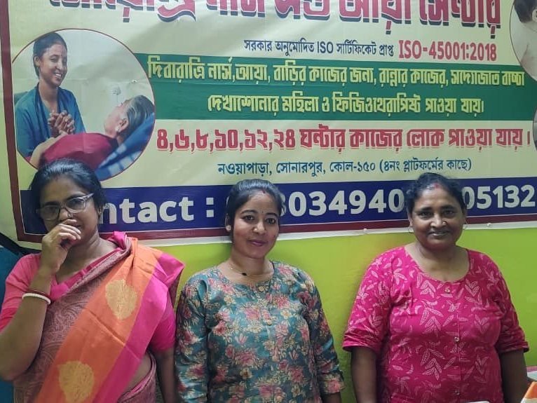 Three Soendri Nurse and Aya Centre caregivers standing in front of the centre signboard in Sonarpur